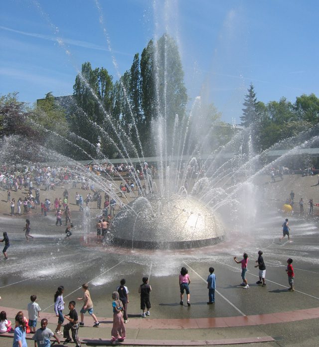 Image of Seattle Center's International Fountain with people playing in the water.