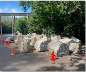 Granite boulders from the DuPen Fountain staged for pickup with orange safety cones placed around them, to be used at the Woodland Park Zoo and Seattle Center Skate Plaza