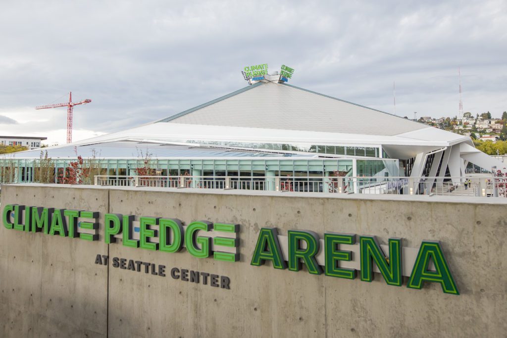 Image of a building, sky, wall with words "Climate Pledge Arena at Seattle Center"