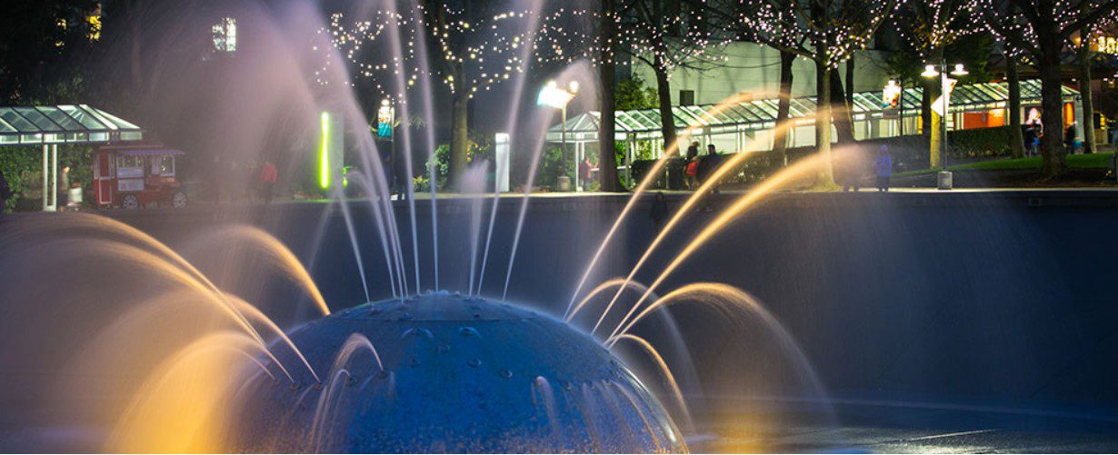 Seattle Center's International Fountain, image by Christopher Nelson.
water, trees, people, building, night time, covered walkway