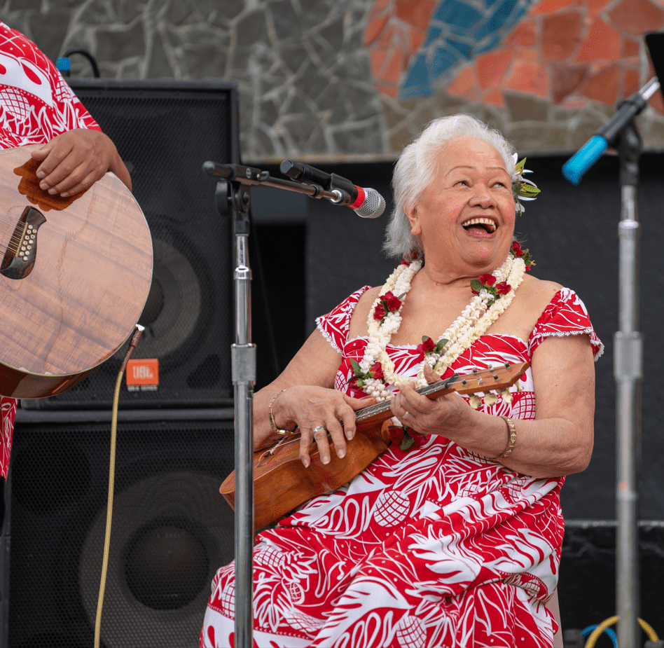 Woman seated and playing instrument. Live Aloha, photo by Susan Fried